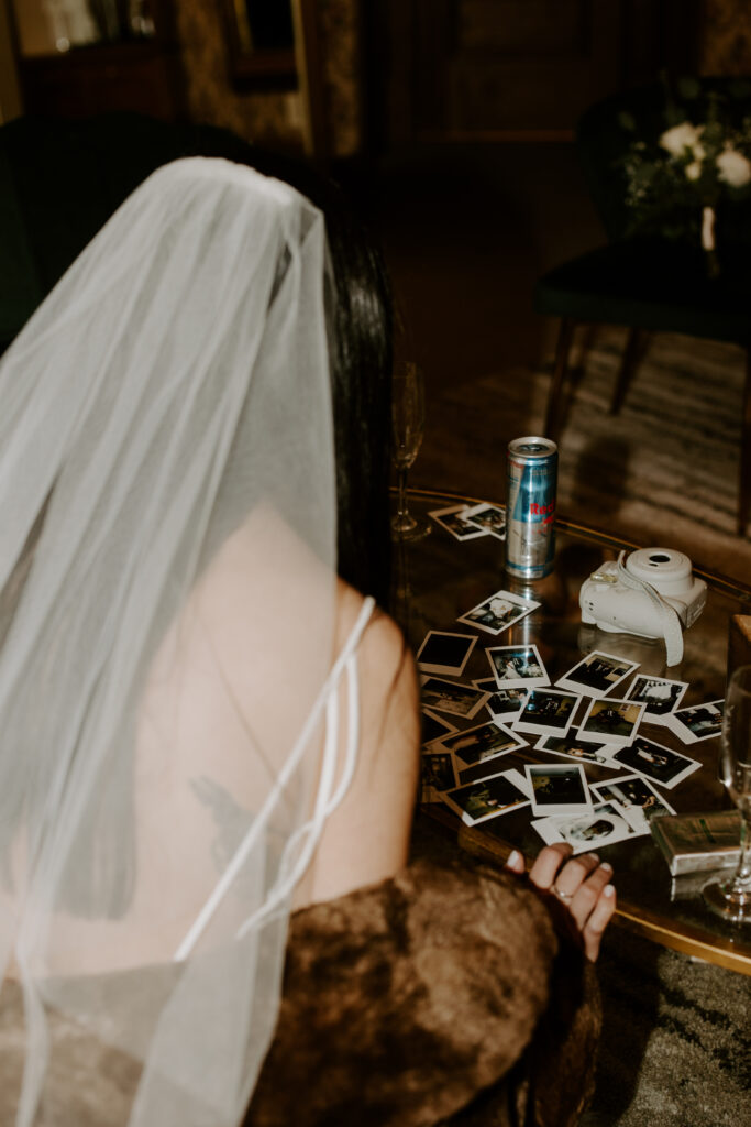 bride looking at polaroids after colorado winter wedding