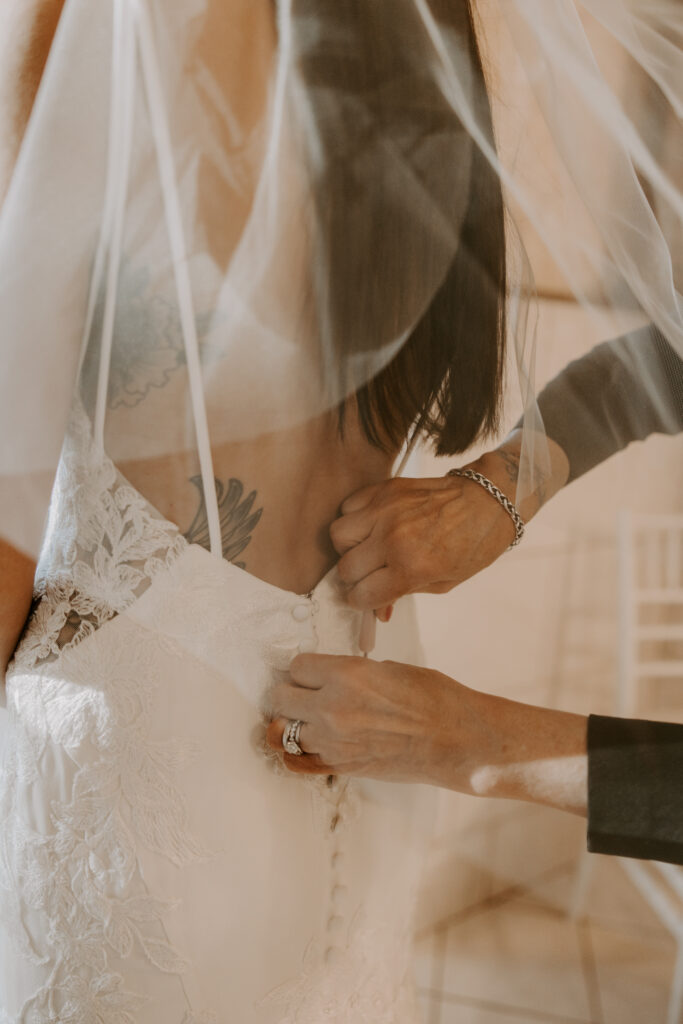 bride getting her wedding dress zipped up